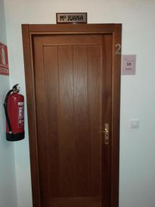 a wooden door with a sign above it and a fire hydrant at La Casa de Mi Abuela in Aldeanueva del Camino