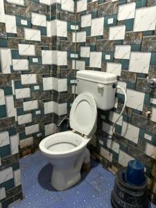 a bathroom with a toilet with a tiled wall at GRG Sunrise Plaza Deoghar in Deoghar