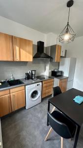 a kitchen with a washing machine and a table at Appartement F5 proche centre ville in Mulhouse