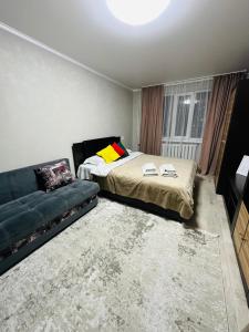 um quarto com uma cama e um sofá em Муканова 6/2 em Karaganda