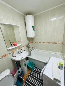 a bathroom with a sink and a toilet and a tub at Муканова 6/2 in Karagandy