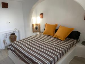 1 cama con almohadas amarillas en una habitación blanca en Villa Xanthos, en Plaka