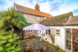 a table with an umbrella in front of a building at Samphire Cottage by Big Skies Cottages in Docking