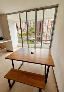 einem Holztisch mit einer Bank vor einem Fenster in der Unterkunft Medellin: Cozy Apat with City View in Envigado