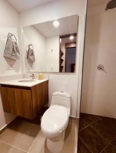 ein Badezimmer mit einem WC, einem Waschbecken und einem Spiegel in der Unterkunft Medellin: Cozy Apat with City View in Envigado
