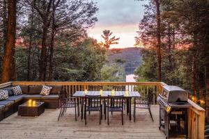 eine Terrasse mit einem Tisch, Stühlen und einem Grill in der Unterkunft Rivers Ledge - 62 Acre Nature Retreat in Eldred