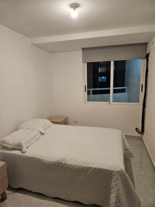 a bedroom with a white bed and a window at Apartamento Bay View Panama cinta costera in Panama City