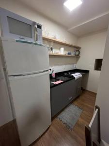 a kitchen with a white refrigerator with a microwave at Studio no centro, novo com garagem in Santa Maria