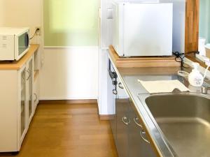 a kitchen with a sink and a microwave at Nomura Building Parkside - Vacation STAY 34551v in Fuji