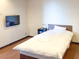 a white bed in a room with a tv on a wall at Nomura Building Parkside - Vacation STAY 34551v in Fuji