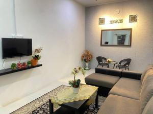 - un salon avec un canapé et une télévision dans l'établissement Uzma Homestay Kuala Sg Baru, Melaka, à Malacca