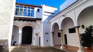 two white buildings with arches and a black door at Preciosa Casa Renovada Centro Histórico 11 personas in Seville