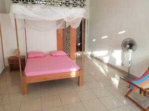 a bed with pink sheets and a canopy in a room at Spices Beach Studio Madirokely Nosy Be in Nosy Be