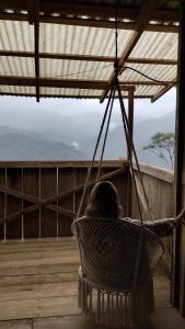 a woman sitting in a hammock on a porch at Finca Del Cielo in El Castillo de la Fortuna