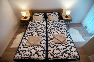 a bed with a black and white comforter and two tables at Mistral Residence 308 in Balatonföldvár +9 photos