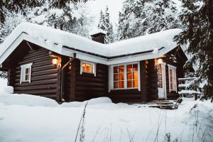 a log cabin in the snow with lights on at Villa Lappee in Kolari