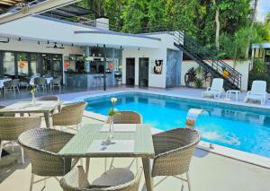 ein Pool mit Tischen und Stühlen vor einem Haus in der Unterkunft Hotel Oasis-Dream Holidays - La Petite France in San Bernardino