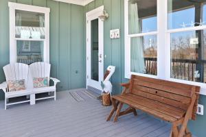a porch with a bench and two white chairs at Havin A Blas by Pristine Properties Vacation Rentals in Cape San Blas