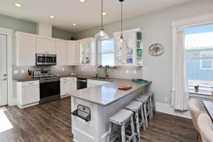 a kitchen with white cabinets and a large island with bar stools at Havin A Blas by Pristine Properties Vacation Rentals in Cape San Blas