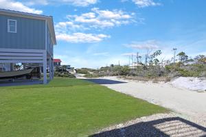 a house with a grassy yard next to a building at Havin A Blas by Pristine Properties Vacation Rentals in Cape San Blas