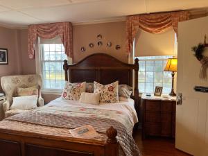 a bedroom with a bed and a chair and windows at Antique1242 British Bed & Breakfast in Enfield