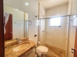 La salle de bains est pourvue d'un lavabo, de toilettes et d'un miroir. dans l'établissement Pousada Villa Magna - Casa 4, à Diamantina