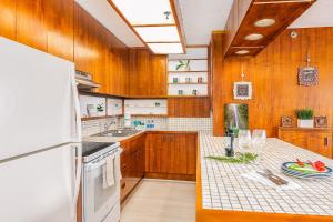 - une cuisine avec des placards en bois et un réfrigérateur blanc dans l'établissement Beautiful Renovated Mountain View Condo with Parking!, à Honolulu