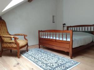 1 dormitorio con 1 cama, 1 silla y 1 alfombra en Loft les Noies Parrons, gîte aux milles étangs en Mélisey