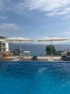 a large swimming pool with umbrellas and the ocean at Entire holiday flat in Sarande in Sarandë