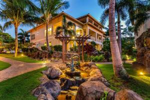 a house with a fountain in front of a yard at Elegant Poolside Penthouse w Private Elevator in Koloa