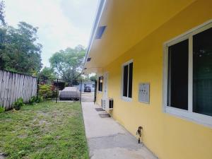 a yellow house with a sidewalk next to a yard at Arpe 4plex in Fort Lauderdale