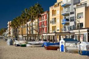 a group of boats on a beach with buildings at Mar & Aventura in Torredembarra