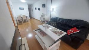 sala de estar con sofá de cuero negro y mesa en Mar & Aventura, en Torredembarra