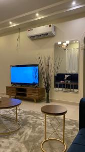 a living room with two tables and a flat screen tv at شقه بصالة انيقة وغرفة نوم . in Al Khobar