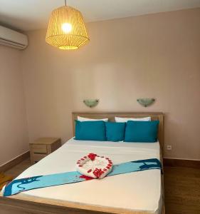 a bedroom with a large bed with blue pillows at LESSENCIEL in Dzaoudzi
