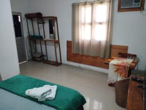 Habitación con cama con manta verde y ventana en Aconchego em Maragogi, en Maragogi