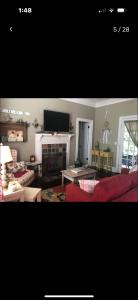 The Cozy Cottage في توماسفيل: غرفة معيشة مع أريكة حمراء ومدفأة