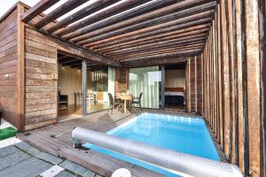 an outdoor swimming pool with a wooden pergola at Cabañas de Mallas in Fisterra