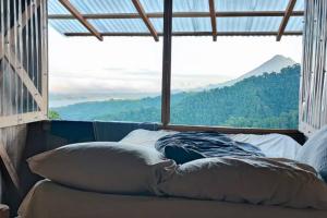 a bed with pillows in a room with a large window at Finca Del Cielo in El Castillo de la Fortuna