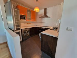 a kitchen with orange cabinets and a washer and dryer at Castro Urdiales Mioño in Mioño