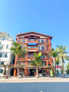 an orange building with palm trees in front of a street at Cánh Buồm Homestay - Tuần Châu in Ha Long