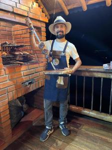 un hombre en un delantal sosteniendo una bandeja de comida en MoiraEcolodge, en Córdoba