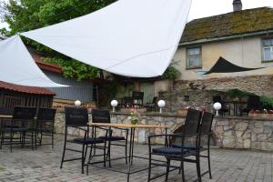 a group of chairs around a table with a white umbrella at Viesnīca Kandava in Kandava
