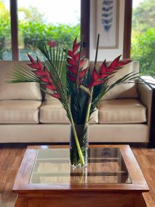 a vase with red flowers sitting on a table at Teanehi Bed & Breakfast in Hanga Roa