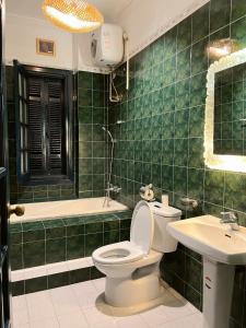ein grün gefliestes Bad mit einem WC und einem Waschbecken in der Unterkunft GÁC home & decor in Hanoi