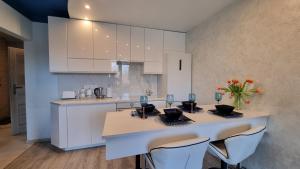 a kitchen with white cabinets and a table with chairs at BLUE APARTMENT in Polanica-Zdrój