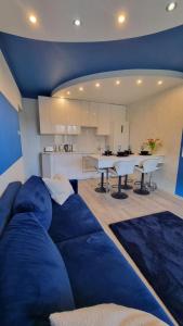 a large blue couch in a room with a kitchen at BLUE APARTMENT in Polanica-Zdrój