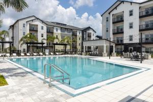 a swimming pool with chairs and a building at Sleek Modern Gateway 10 Min to Parks Pets Allowed in Orlando