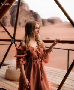 a woman in a brown dress standing next to the beach at Nasem rum in Wadi Rum