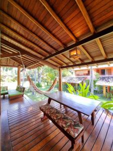 a wooden deck with a hammock and a table and chairs at Paraíso Tropical desejado Centro de Arraial in Arraial d'Ajuda